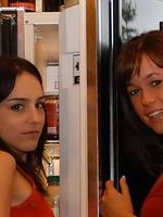two fabulous lesbians playing with food next to the fridge