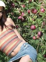 beautiful young brunette licking a red apple in the sun